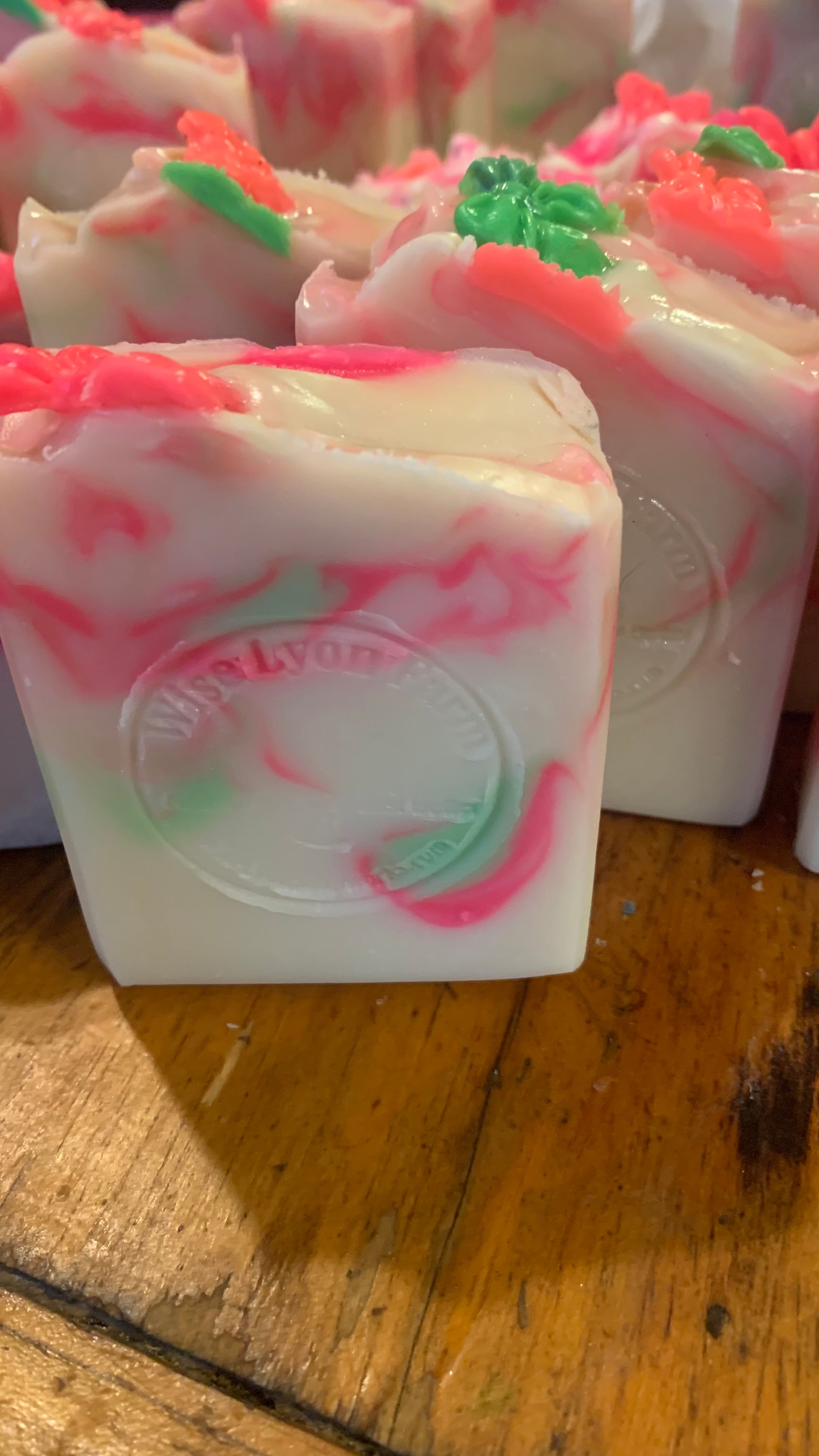 Handmade bar of honeysuckle soap that is beige in color with bright pink and green swirls made by Wise Lyon Soapworks